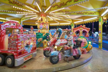 İtalya, Sicilya, Marina di Ragusa (Ragusa Eyaleti), 20 Temmuz 2021, bir lunaparkta geceleyin atlıkarıncalı insanlar