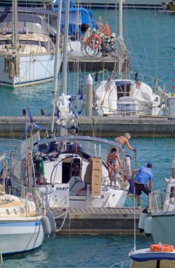 İtalya, Sicilya, Akdeniz, Marina di Ragusa (Ragusa ili); 29 Temmuz 2021, limandaki bir yelkenli teknesinde insanlar - EDITORIAL