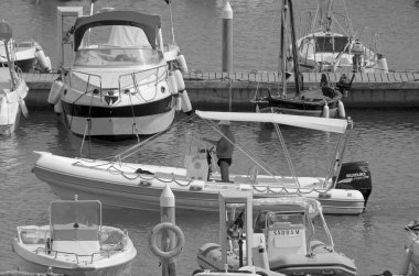 İtalya, Sicilya, Akdeniz, Marina di Ragusa (Ragusa Eyaleti); 30 Temmuz 2021, limandaki kauçuk bir tekne ve lüks yatlarda adam - EDITORIAL