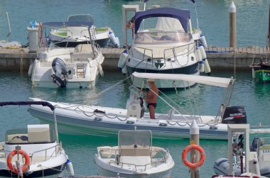 İtalya, Sicilya, Akdeniz, Marina di Ragusa (Ragusa Eyaleti); 30 Temmuz 2021, limandaki kauçuk bir tekne ve lüks yatlarda adam - EDITORIAL