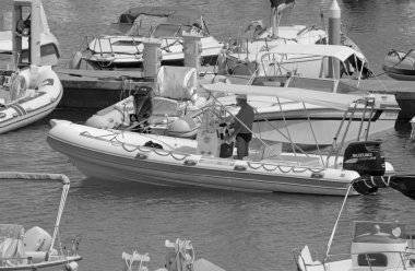 İtalya, Sicilya, Akdeniz, Marina di Ragusa (Ragusa Eyaleti); 30 Temmuz 2021, limandaki kauçuk bir tekne ve lüks yatlarda adam - EDITORIAL