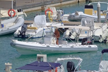 İtalya, Sicilya, Akdeniz, Marina di Ragusa (Ragusa Eyaleti); 30 Temmuz 2021, limandaki kauçuk bir tekne ve lüks yatlarda adam - EDITORIAL