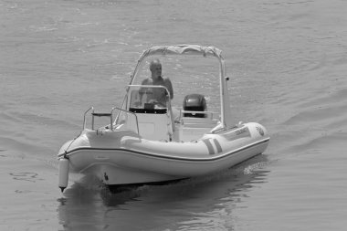 İtalya, Sicilya, Akdeniz, Marina di Ragusa (Ragusa Eyaleti); 1 Ağustos 2021, limandaki kauçuk bir teknede adam - EDITORIAL