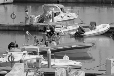 İtalya, Sicilya, Akdeniz, Marina di Ragusa (Ragusa Eyaleti); 1 Ağustos 2021, limandaki kauçuk tekne ve lüks yatlarda yaşayan insanlar - EDITORIAL