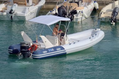 İtalya, Sicilya, Akdeniz, Marina di Ragusa (Ragusa Eyaleti); 1 Ağustos 2021, limandaki kauçuk bir tekne ve lüks yatlarda adam - EDITORIAL