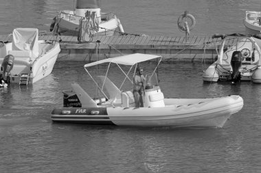 İtalya, Sicilya, Akdeniz, Marina di Ragusa (Ragusa Eyaleti); 1 Ağustos 2021, limandaki kauçuk bir tekne ve lüks yatlarda adam - EDITORIAL