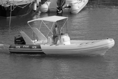 İtalya, Sicilya, Akdeniz, Marina di Ragusa (Ragusa Eyaleti); 1 Ağustos 2021, limandaki kauçuk bir tekne ve lüks yatlarda adam - EDITORIAL