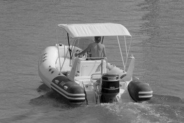 İtalya, Sicilya, Akdeniz, Marina di Ragusa (Ragusa Eyaleti); 1 Ağustos 2021, limandaki kauçuk bir teknede adam - EDITORIAL