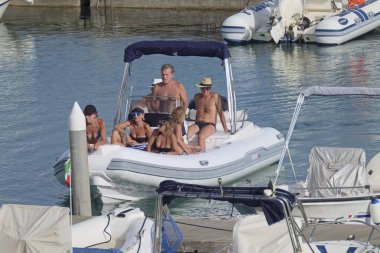 İtalya, Sicilya, Akdeniz, Marina di Ragusa (Ragusa Eyaleti); 1 Ağustos 2021, limandaki kauçuk tekne ve lüks yatlarda yaşayan insanlar - EDITORIAL