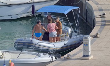 İtalya, Sicilya, Akdeniz, Marina di Ragusa (Ragusa ili); 2 Ağustos 2021, limandaki kauçuk bir teknede insanlar - EDITORIAL