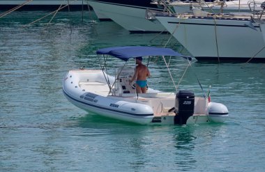 İtalya, Sicilya, Akdeniz, Marina di Ragusa (Ragusa Eyaleti); 4 Ağustos 2021, limanda kauçuk bir tekne ve lüks yatlarda adam - EDITORIAL