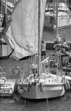 İtalya, Sicilya, Akdeniz, Marina di Ragusa (Ragusa ili); 5 Ağustos 2021, limanda bir yelkenli ve lüks yatlarda erkekler - EDITORIAL