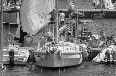 İtalya, Sicilya, Akdeniz, Marina di Ragusa (Ragusa ili); 5 Ağustos 2021, limanda bir yelkenli ve lüks yatlarda erkekler - EDITORIAL