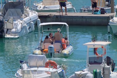 İtalya, Sicilya, Akdeniz, Marina di Ragusa (Ragusa ili); 7 Ağustos 2021, limandaki kauçuk bir tekne ve lüks yatlarda yaşayan insanlar - EDITORIAL