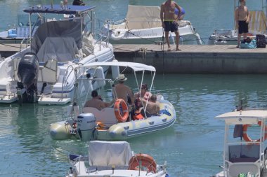 İtalya, Sicilya, Akdeniz, Marina di Ragusa (Ragusa ili); 7 Ağustos 2021, limandaki kauçuk bir tekne ve lüks yatlarda yaşayan insanlar - EDITORIAL