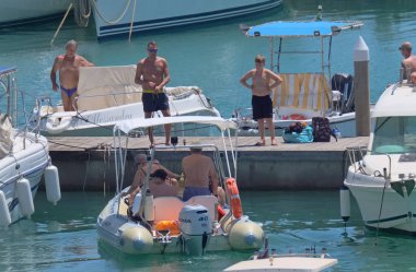 İtalya, Sicilya, Akdeniz, Marina di Ragusa (Ragusa ili); 7 Ağustos 2021, limandaki kauçuk bir tekne ve lüks yatlarda yaşayan insanlar - EDITORIAL