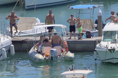 İtalya, Sicilya, Akdeniz, Marina di Ragusa (Ragusa ili); 7 Ağustos 2021, limandaki kauçuk bir tekne ve lüks yatlarda yaşayan insanlar - EDITORIAL