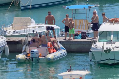 İtalya, Sicilya, Akdeniz, Marina di Ragusa (Ragusa ili); 7 Ağustos 2021, limandaki kauçuk bir tekne ve lüks yatlarda yaşayan insanlar - EDITORIAL