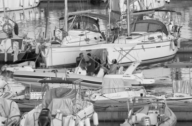 İtalya, Sicilya, Akdeniz, Marina di Ragusa (Ragusa ili); 7 Ağustos 2021, limandaki kauçuk bir tekne ve lüks yatlarda yaşayan insanlar - EDITORIAL