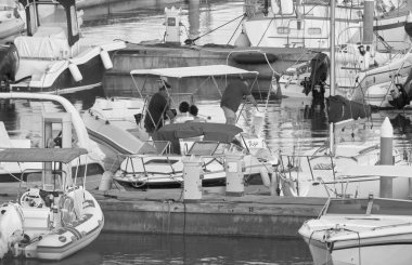 İtalya, Sicilya, Akdeniz, Marina di Ragusa (Ragusa ili); 7 Ağustos 2021, limandaki kauçuk bir tekne ve lüks yatlarda yaşayan insanlar - EDITORIAL