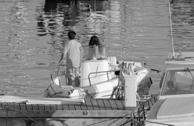 İtalya, Sicilya, Akdeniz, Marina di Ragusa (Ragusa Eyaleti); limanda bir motorlu teknede çift 