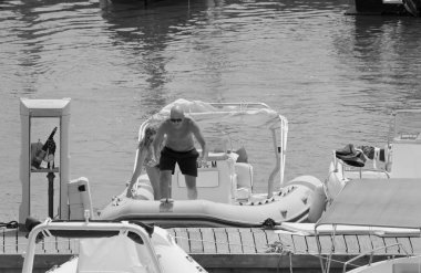 İtalya, Sicilya, Akdeniz, Marina di Ragusa (Ragusa ili); 12 Ağustos 2021, limanda kauçuk bir tekne ve lüks yatlarda bir çift - EDITORIAL