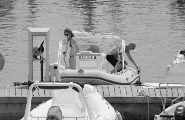 İtalya, Sicilya, Akdeniz, Marina di Ragusa (Ragusa ili); 12 Ağustos 2021, limanda kauçuk bir tekne ve lüks yatlarda bir çift - EDITORIAL