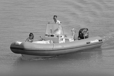 İtalya, Sicilya, Akdeniz, Marina di Ragusa (Ragusa ili); 12 Ağustos 2021, limanda kauçuk bir tekne ve lüks yatlarda bir çift - EDITORIAL