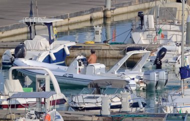 İtalya, Sicilya, Akdeniz, Marina di Ragusa (Ragusa Eyaleti); 13 Ağustos 2021, limandaki kauçuk bir tekne ve lüks yatlarda adam - EDITORIAL