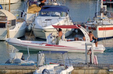 İtalya, Sicilya, Akdeniz, Marina di Ragusa (Ragusa ili); 14 Ağustos 2021, limandaki kauçuk bir tekne ve lüks yatlarda yaşayan insanlar - EDITORIAL