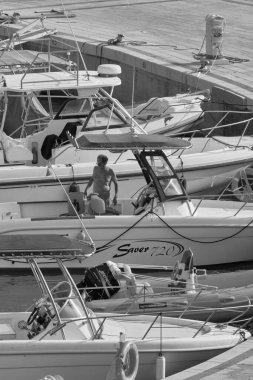 İtalya, Sicilya, Akdeniz, Marina di Ragusa (Ragusa Eyaleti); 15 Ağustos 2021, limanda bir motorlu tekne ve lüks yatlarda adam - EDITORIAL