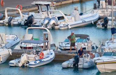 İtalya, Sicilya, Akdeniz, Marina di Ragusa (Ragusa Eyaleti); 19 Ağustos 2021, gün batımında limanda halk, motorlu tekne ve lüks yatlar - EDITORIAL