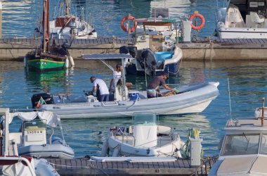 İtalya, Sicilya, Akdeniz, Marina di Ragusa (Ragusa ili); 21 Ağustos 2021, limandaki kauçuk bir tekne ve lüks yatlarda erkekler - EDITORIAL