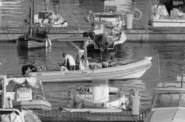 İtalya, Sicilya, Akdeniz, Marina di Ragusa (Ragusa ili); 21 Ağustos 2021, limandaki kauçuk bir tekne ve lüks yatlarda erkekler - EDITORIAL