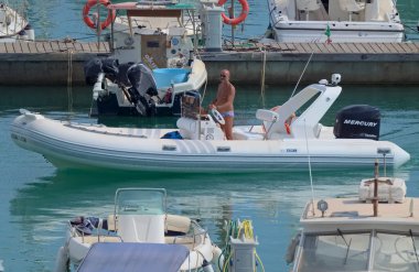 İtalya, Sicilya, Akdeniz, Marina di Ragusa (Ragusa Eyaleti); 22 Ağustos 2021, limandaki kauçuk bir tekne ve lüks yatlarda adam - EDITORIAL