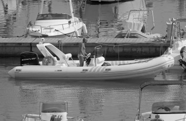 İtalya, Sicilya, Akdeniz, Marina di Ragusa (Ragusa Eyaleti); 22 Ağustos 2021, limandaki kauçuk bir tekne ve lüks yatlarda adam - EDITORIAL