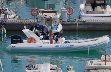 İtalya, Sicilya, Akdeniz, Marina di Ragusa (Ragusa Eyaleti); 22 Ağustos 2021, limandaki kauçuk bir tekne ve lüks yatlarda adam - EDITORIAL