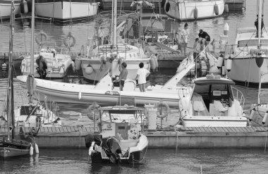 İtalya, Sicilya, Akdeniz, Marina di Ragusa (Ragusa ili); 22 Ağustos 2021, limanda kauçuk bir tekne ve lüks yatlarda bir çift - EDITORIAL