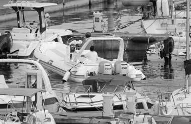 İtalya, Sicilya, Akdeniz, Marina di Ragusa (Ragusa ili); 22 Ağustos 2021, limanda kauçuk bir tekne ve lüks yatlarda bir çift - EDITORIAL