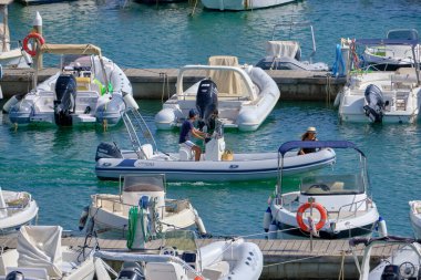 İtalya, Sicilya, Akdeniz, Marina di Ragusa (Ragusa ili); 24 Ağustos 2021, limanda kauçuk bir tekne ve lüks yatlarda bir çift - EDITORIAL