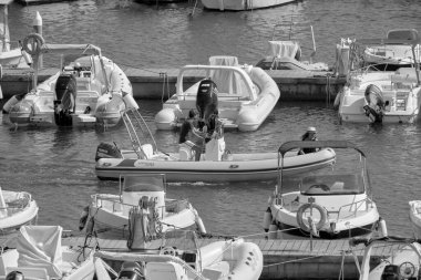 İtalya, Sicilya, Akdeniz, Marina di Ragusa (Ragusa ili); 24 Ağustos 2021, limanda kauçuk bir tekne ve lüks yatlarda bir çift - EDITORIAL