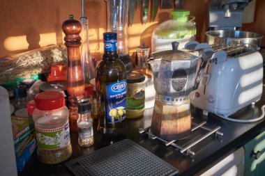 İtalya, Sicilya, Marina di Ragusa (Ragusa Eyaleti); 27 Ağustos 2021, mutfak tezgahında yemek pişirme malzemeleri ve baharatlar, bir pencereden gelen güneş ışınlarıyla aydınlatılıyor - EDITORIAL