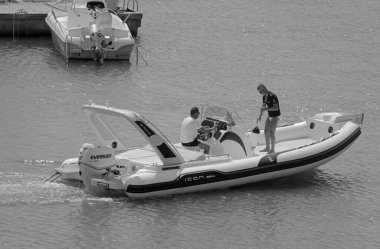 İtalya, Sicilya, Akdeniz, Marina di Ragusa (Ragusa Eyaleti); 12 Eylül 2021, limanda bir kauçuk teknede erkekler - EDITORIAL