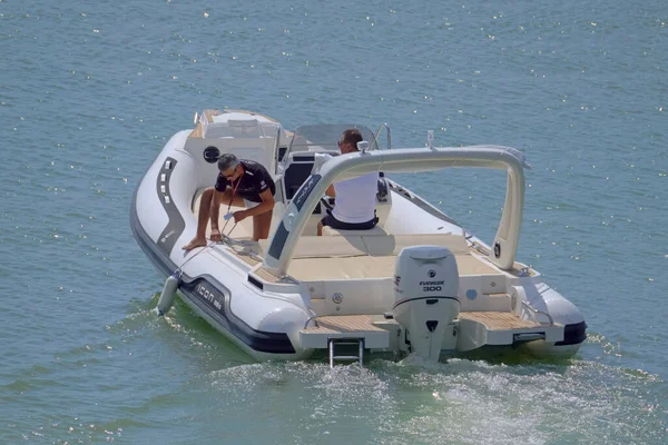 İtalya, Sicilya, Akdeniz, Marina di Ragusa (Ragusa Eyaleti); 12 Eylül 2021, limanda bir kauçuk teknede erkekler - EDITORIAL