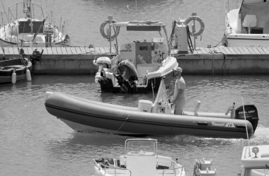 İtalya, Sicilya, Akdeniz, Marina di Ragusa (Ragusa Eyaleti); 12 Eylül 2021, limandaki bir lastik teknede adam - EDITORIAL