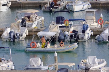 İtalya, Sicilya, Akdeniz, Marina di Ragusa (Ragusa Eyaleti); 17 Eylül 2021, limanda kauçuk bir tekne ve lüks yatlarda bir çift - EDITORIAL