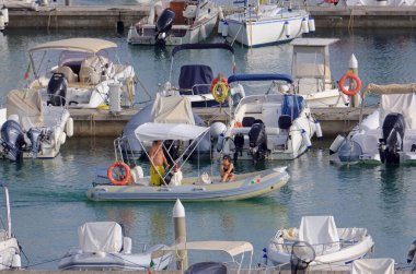 İtalya, Sicilya, Akdeniz, Marina di Ragusa (Ragusa Eyaleti); 17 Eylül 2021, limanda kauçuk bir tekne ve lüks yatlarda bir çift - EDITORIAL