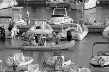 İtalya, Sicilya, Akdeniz, Marina di Ragusa (Ragusa Eyaleti); 17 Eylül 2021, limanda kauçuk bir tekne ve lüks yatlarda bir çift - EDITORIAL