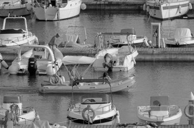 İtalya, Sicilya, Akdeniz, Marina di Ragusa (Ragusa Eyaleti); 17 Eylül 2021, limanda kauçuk bir tekne ve lüks yatlarda bir çift - EDITORIAL