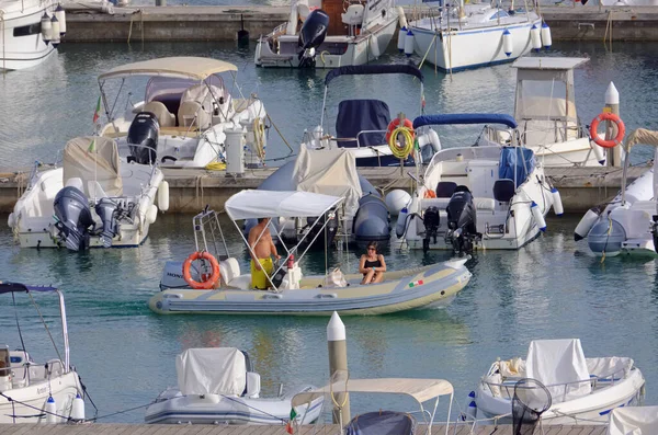 İtalya, Sicilya, Akdeniz, Marina di Ragusa (Ragusa Eyaleti); 17 Eylül 2021, limanda kauçuk bir tekne ve lüks yatlarda bir çift - EDITORIAL